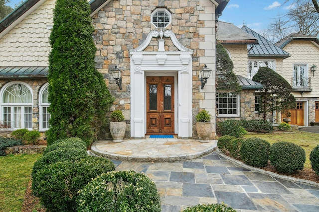 property entrance with metal roof, stone siding, and a standing seam roof