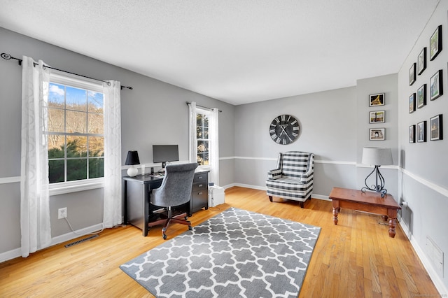 office area featuring visible vents, baseboards, and wood finished floors