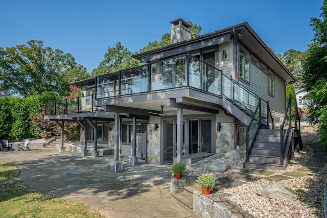 rear view of house featuring a wooden deck, a patio, a chimney, and stairs