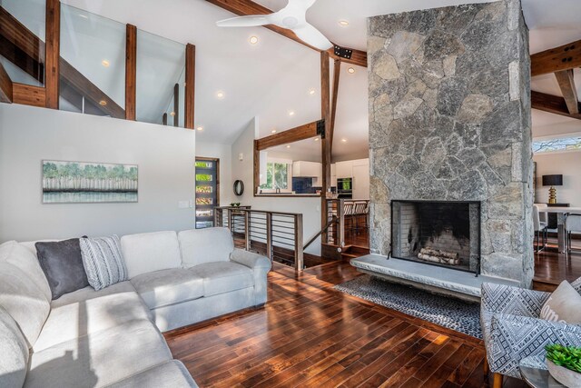 living area featuring beam ceiling, a healthy amount of sunlight, wood finished floors, and a fireplace