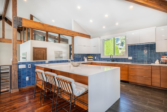 kitchen with a sink, a kitchen breakfast bar, modern cabinets, and white cabinetry