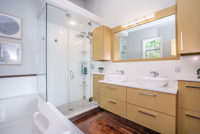 bathroom featuring a bath, wood finished floors, a stall shower, and a sink