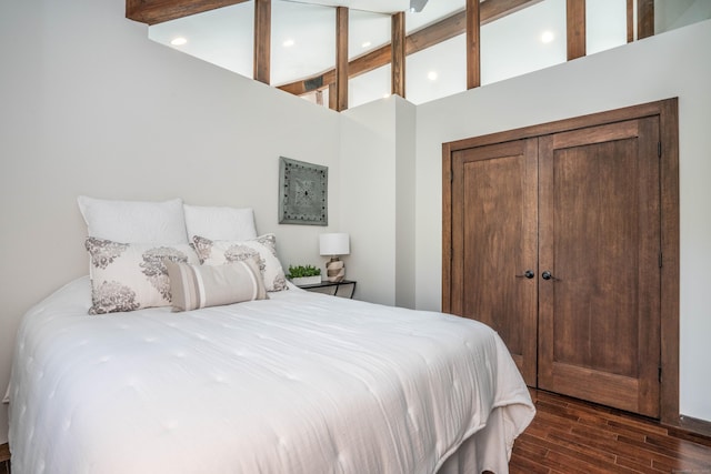 bedroom with dark wood finished floors, beam ceiling, and a closet