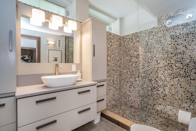 bathroom with visible vents, tiled shower, and vanity