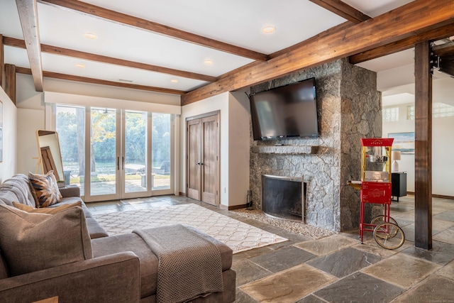 living room with beamed ceiling, baseboards, stone tile flooring, and a fireplace