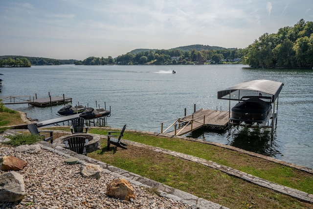 view of dock with boat lift, an outdoor fire pit, and a water view