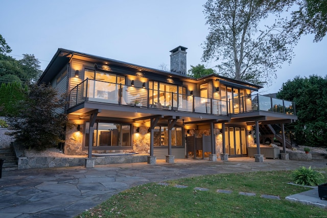 back of property featuring a balcony, a chimney, and a patio area