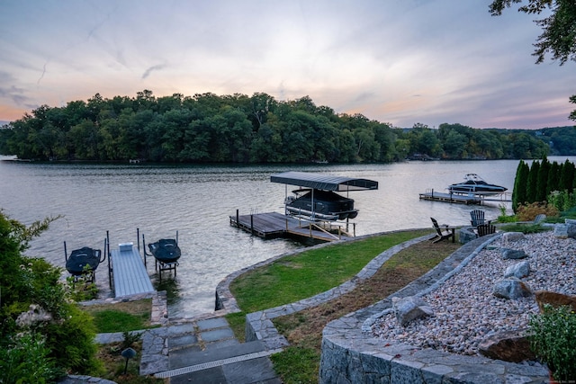 dock area with a view of trees, a water view, and boat lift