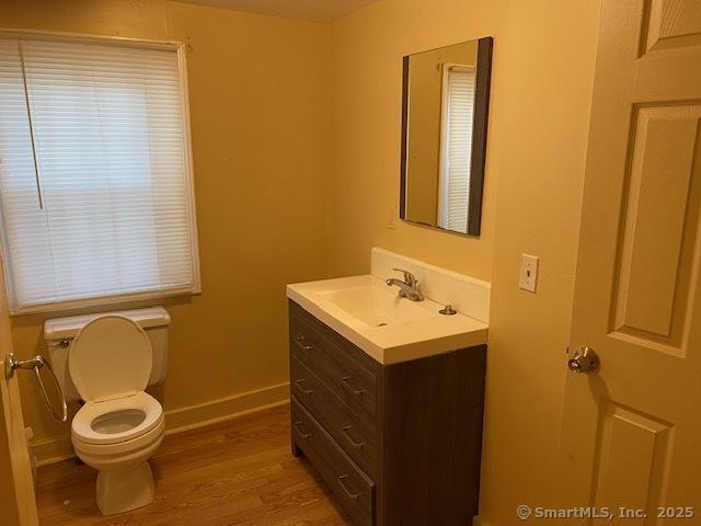 bathroom featuring vanity, toilet, wood finished floors, and baseboards