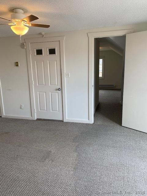 carpeted spare room with ceiling fan, baseboards, baseboard heating, and a textured ceiling