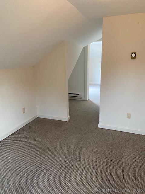 bonus room with a baseboard heating unit, carpet flooring, baseboards, and a textured ceiling