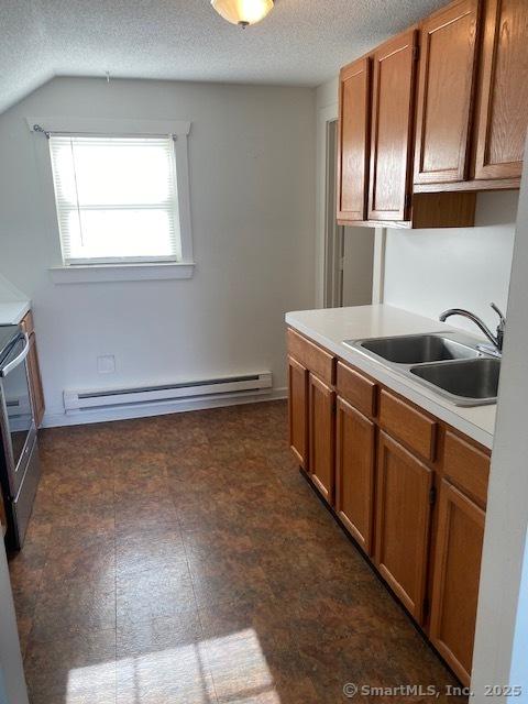 kitchen featuring brown cabinets, a sink, a baseboard heating unit, stainless steel electric stove, and light countertops