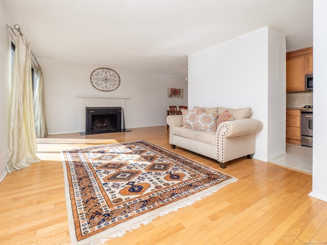 living area with light wood-type flooring and a tile fireplace