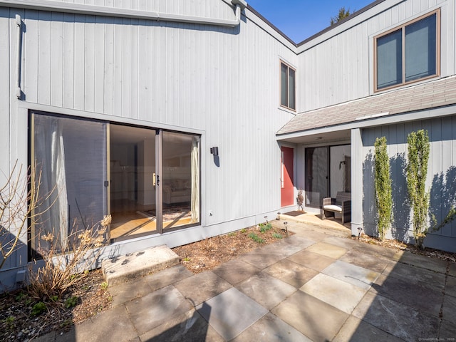 rear view of house with a patio and roof with shingles