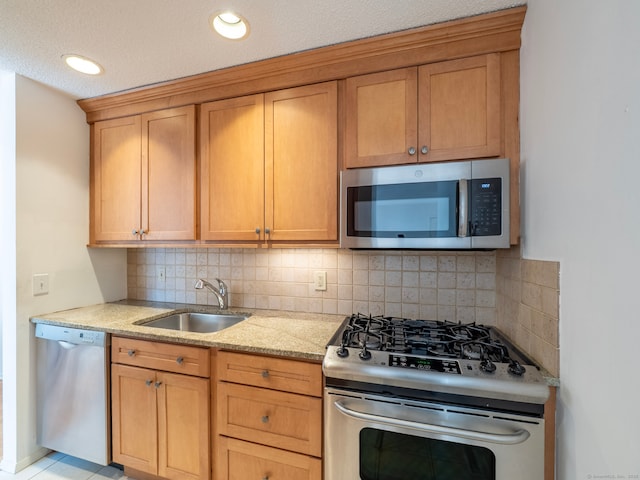 kitchen featuring backsplash, light stone counters, recessed lighting, appliances with stainless steel finishes, and a sink