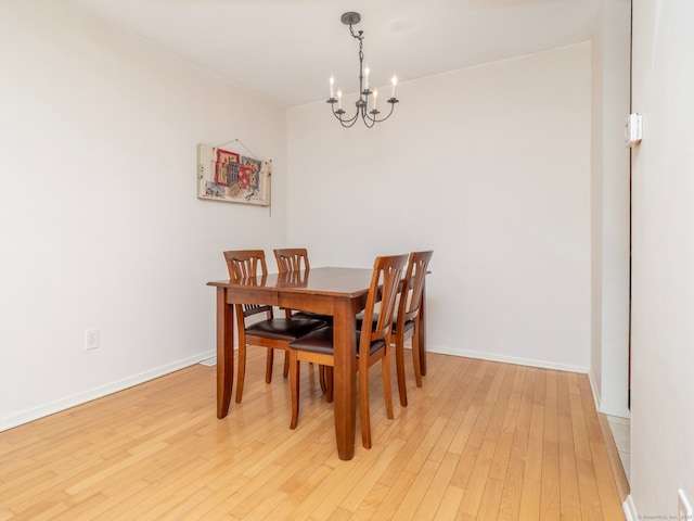 dining room with light wood-style flooring, a notable chandelier, and baseboards