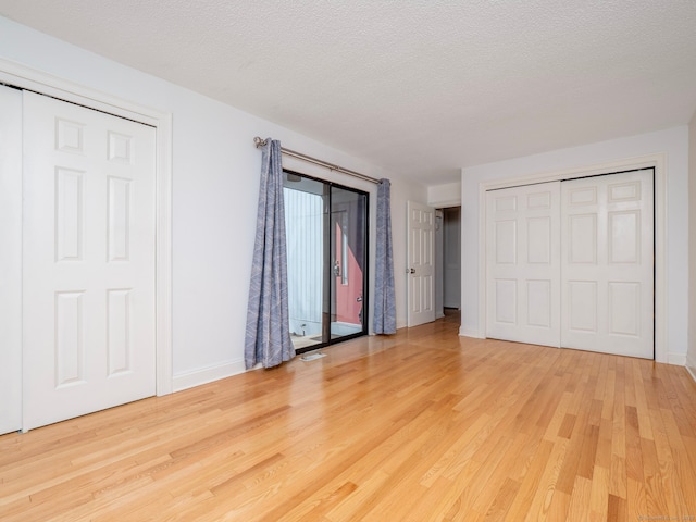 unfurnished bedroom with wood finished floors, baseboards, and a textured ceiling