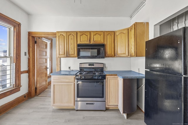 kitchen featuring dark countertops, light wood-style flooring, black appliances, and baseboards