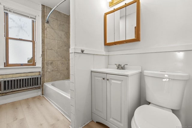 bathroom featuring toilet, shower / tub combination, wood finished floors, radiator, and vanity