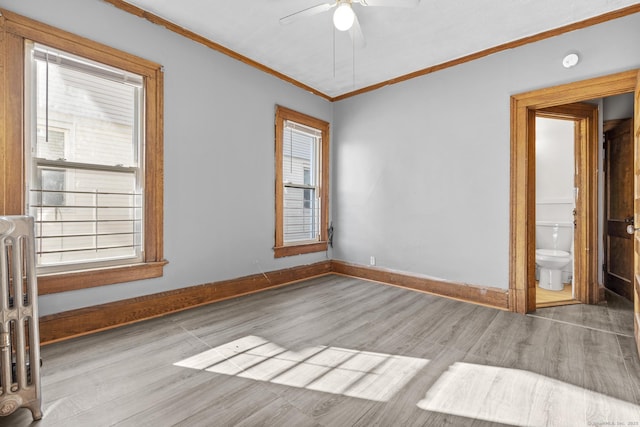 unfurnished room featuring ornamental molding, wood finished floors, radiator heating unit, baseboards, and ceiling fan