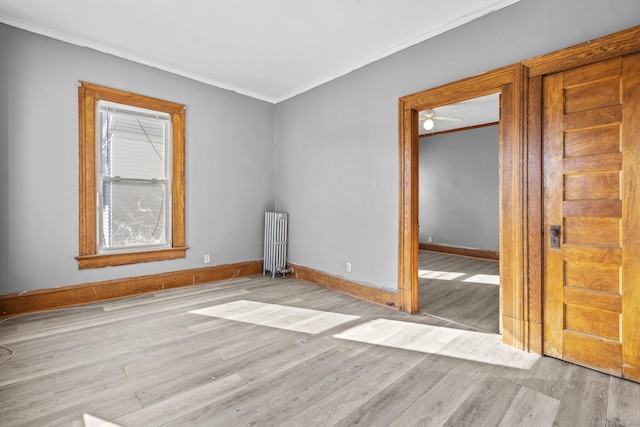 unfurnished room with baseboards, wood finished floors, radiator heating unit, and crown molding