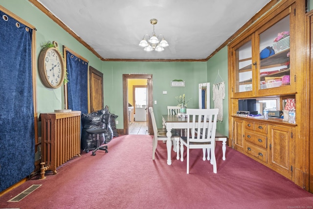 carpeted dining space featuring crown molding, radiator, visible vents, and a chandelier