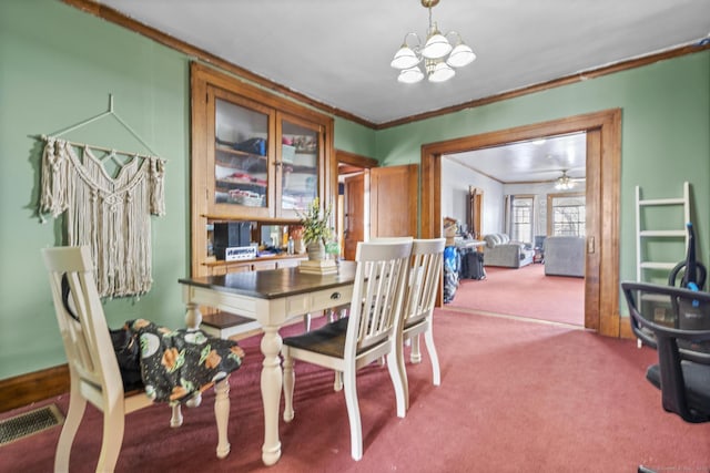 carpeted dining space with a notable chandelier, crown molding, and visible vents