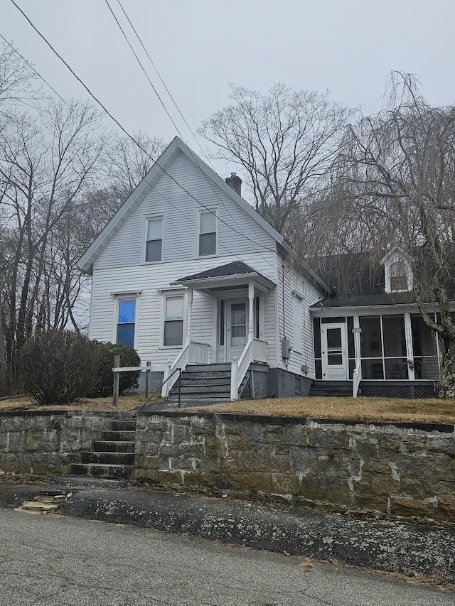 view of front facade featuring a sunroom and a chimney