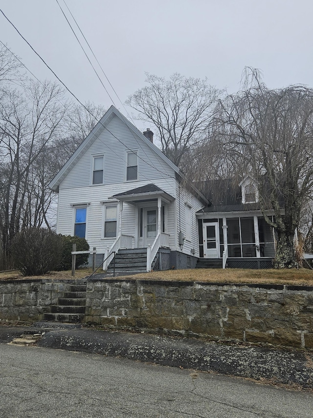 view of front facade with a chimney and a sunroom