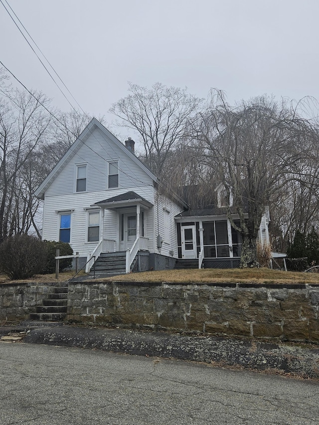 view of front facade featuring a chimney and a sunroom