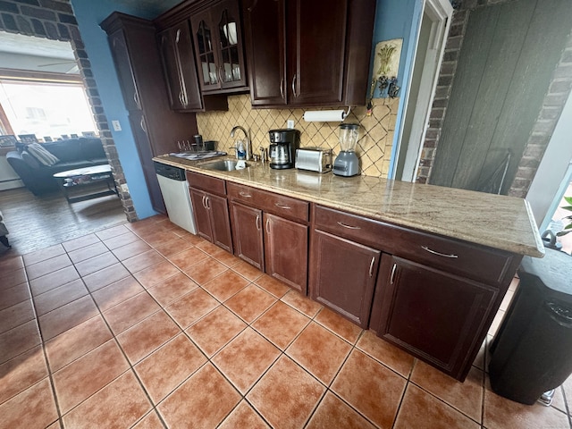 kitchen with a sink, backsplash, light tile patterned flooring, glass insert cabinets, and dishwasher