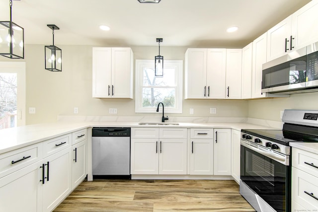 kitchen with light wood-type flooring, a sink, white cabinetry, stainless steel appliances, and a peninsula