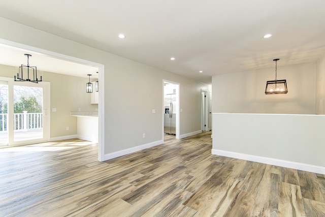 empty room with recessed lighting, an inviting chandelier, wood finished floors, and baseboards