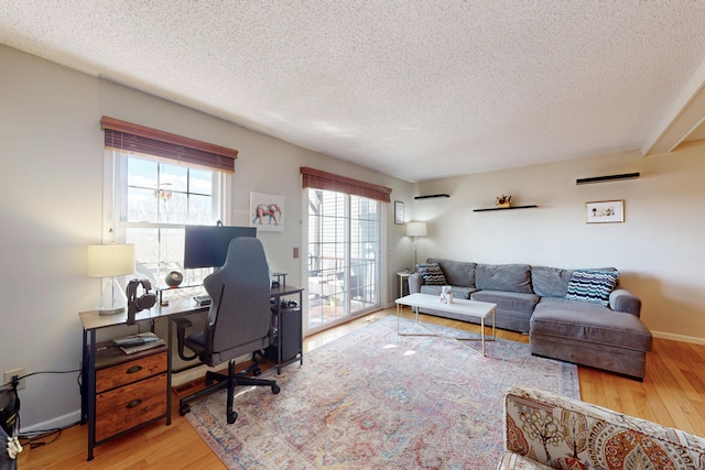 home office featuring baseboards, wood-type flooring, and a textured ceiling