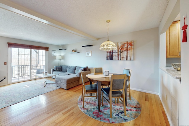 dining room with visible vents, beam ceiling, a notable chandelier, a textured ceiling, and light wood-style floors