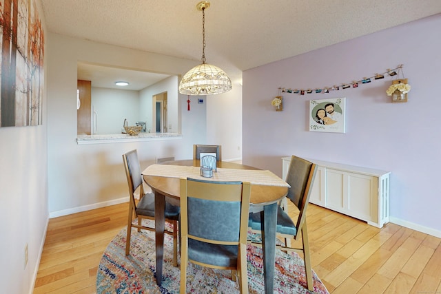 dining area featuring a chandelier, baseboards, a textured ceiling, and wood finished floors