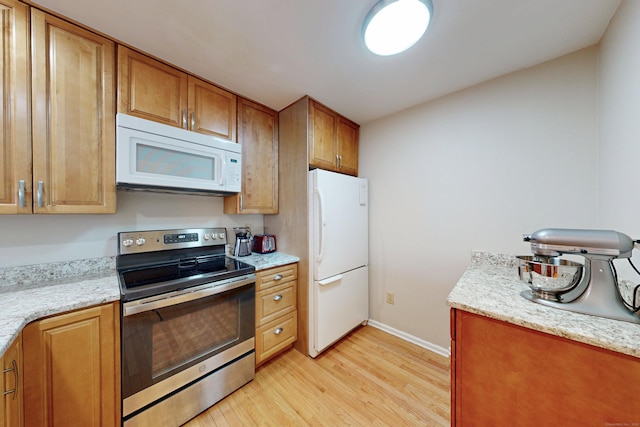 kitchen featuring white appliances, light stone countertops, baseboards, light wood finished floors, and brown cabinets