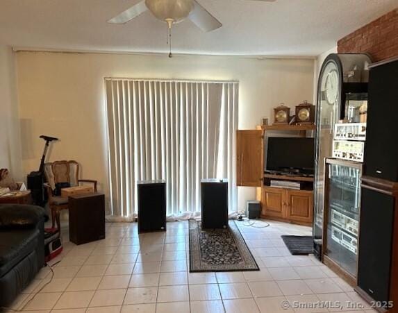 living area with light tile patterned floors and ceiling fan