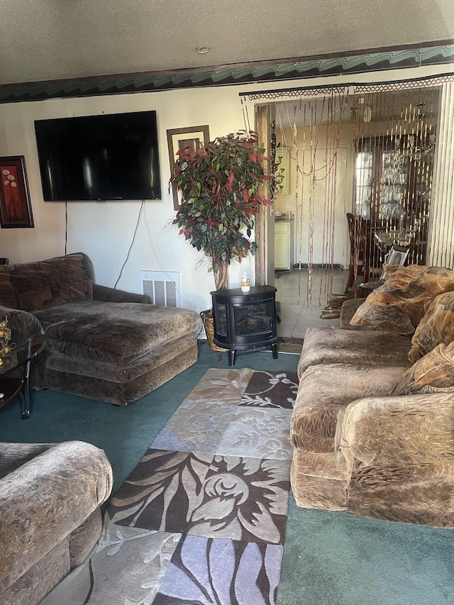 living room featuring visible vents, a textured ceiling, a wood stove, and carpet floors