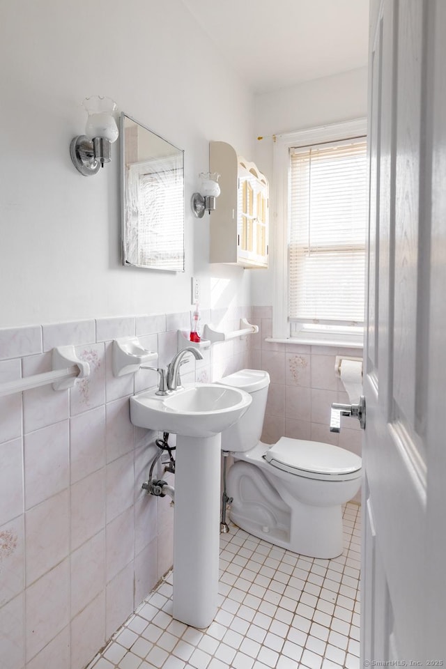 bathroom featuring toilet, tile walls, wainscoting, and tile patterned flooring