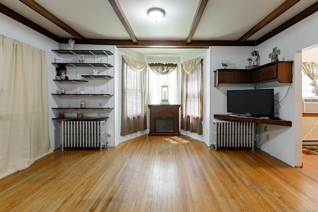 unfurnished living room with radiator heating unit, a glass covered fireplace, hardwood / wood-style flooring, and beamed ceiling