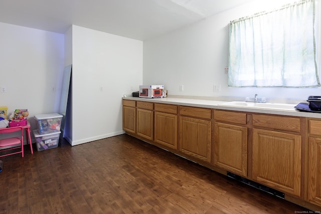 kitchen with brown cabinets, light countertops, a sink, and dark wood finished floors