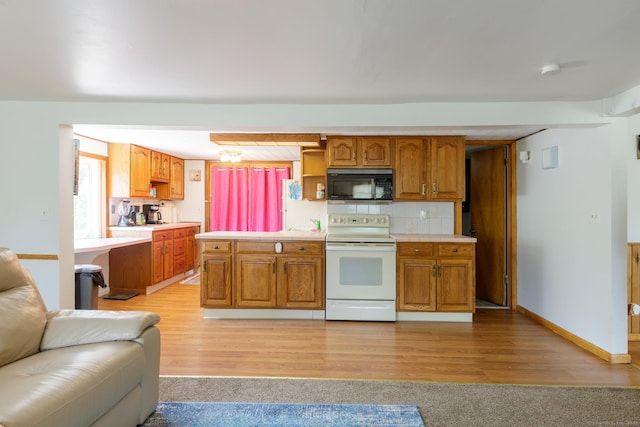 kitchen featuring black microwave, light wood-style flooring, light countertops, open floor plan, and white range with electric stovetop
