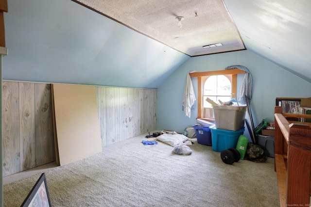 bonus room featuring wooden walls, carpet floors, visible vents, and vaulted ceiling