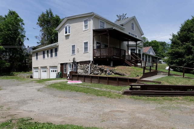 back of property featuring an attached garage, driveway, and stairs