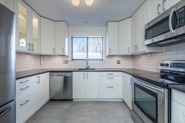 kitchen featuring a sink, stainless steel appliances, dark countertops, and white cabinets