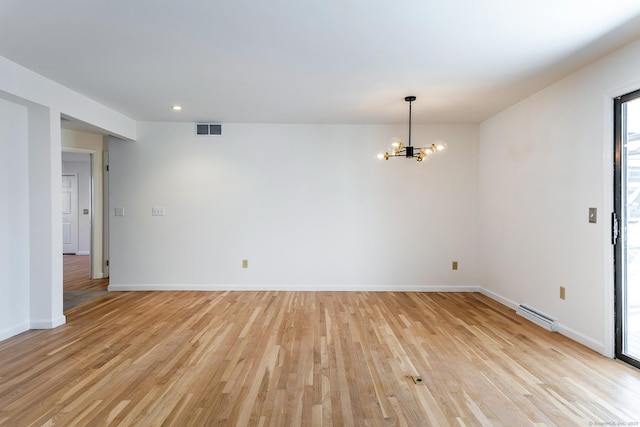 spare room with light wood-type flooring, visible vents, baseboards, and an inviting chandelier