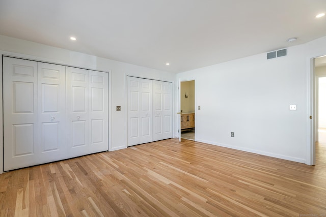 unfurnished bedroom with visible vents, two closets, baseboards, light wood-type flooring, and recessed lighting