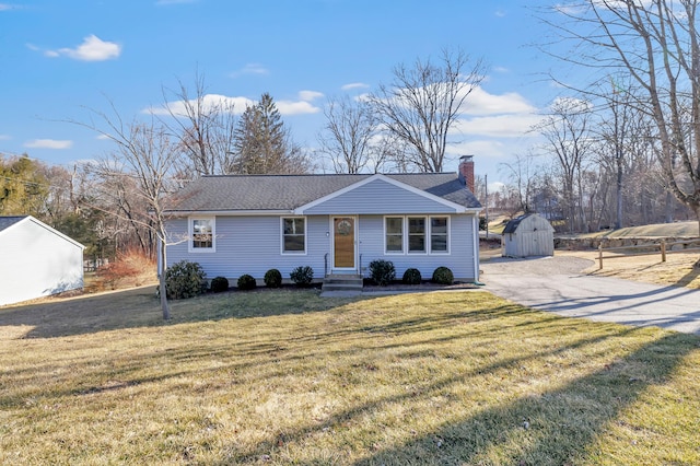 view of front of house featuring an outbuilding, a front lawn, entry steps, a shed, and a chimney