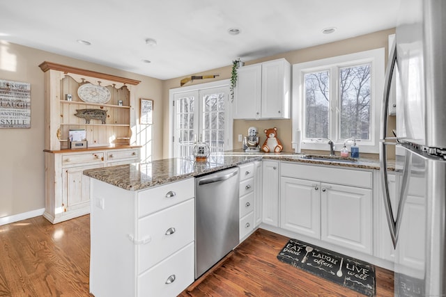 kitchen with dark wood finished floors, a peninsula, open shelves, a sink, and appliances with stainless steel finishes